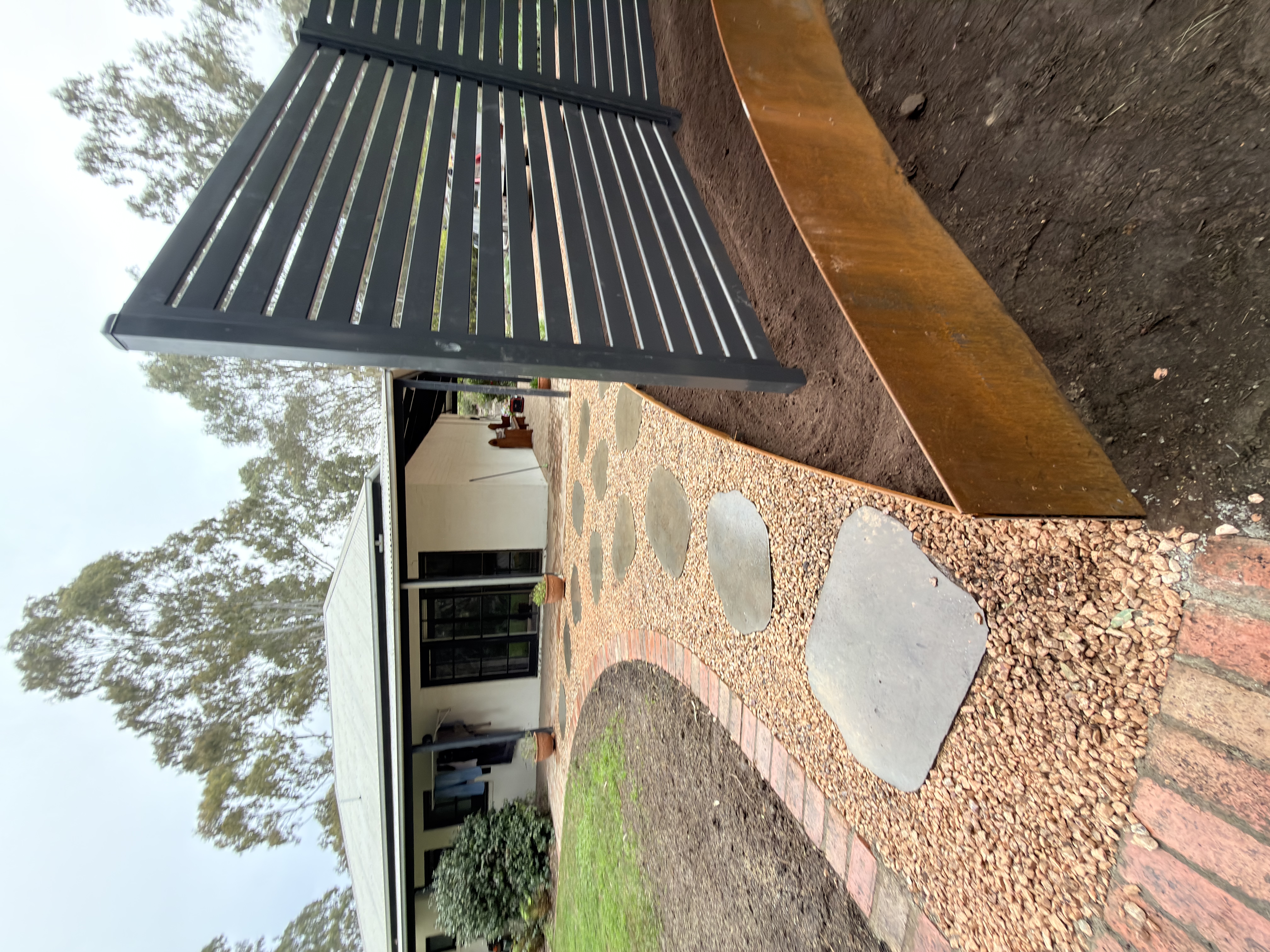 Completed Tex Fox Landscapes entrance with natural stone steppers, gravel path, brick edging and Corten garden border